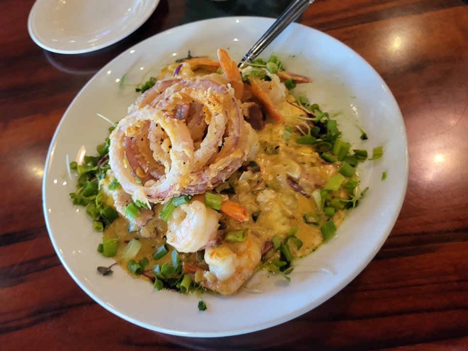 Shrimp and grits topped with onion rings at Castaways Sandfly, wider angle.