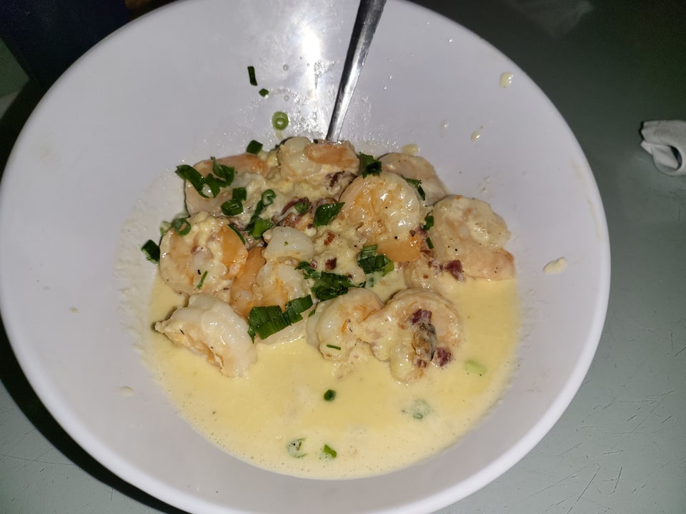 Shrimp in a cream sauce with green onions in a white bowl at Driftaway Cafe.