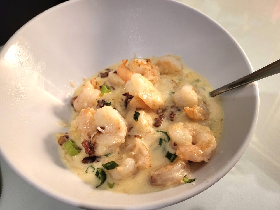 Shrimp in a creamy sauce with herbs in a white bowl at Driftaway Cafe.