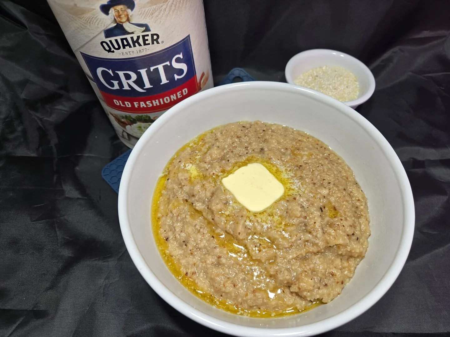 The bowl of dark-toasted grits beside the Quaker Old Fashioned grits canister and a small dish of dry grits