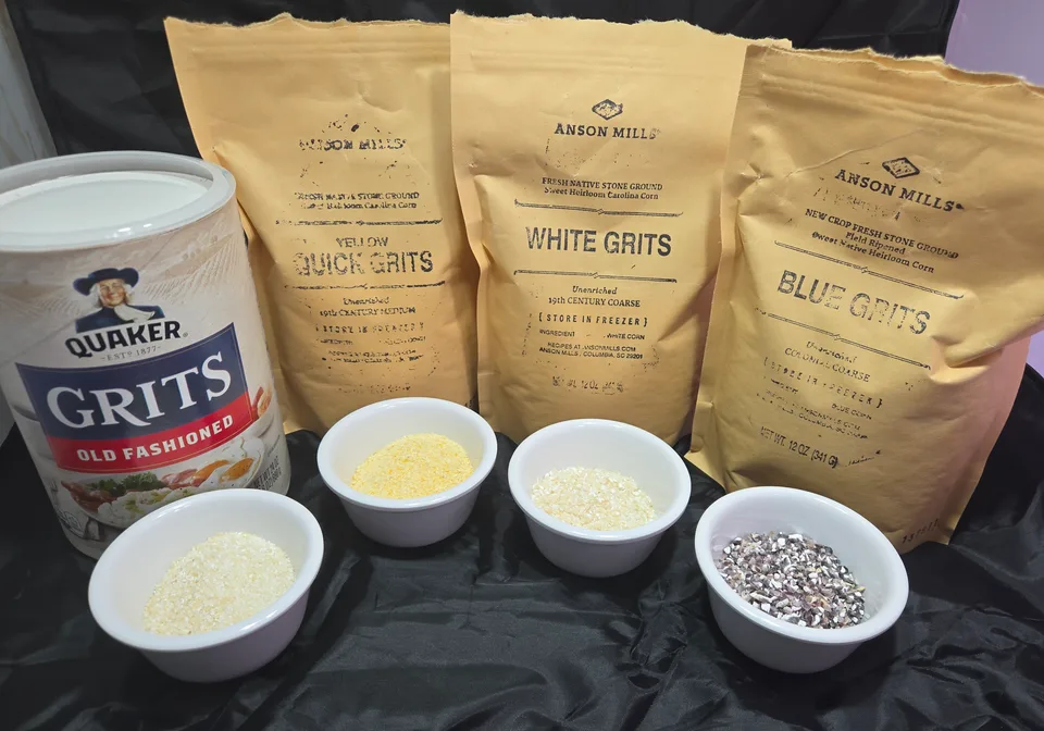 A canister of Quaker Old Fashioned grits and three paper bags of Anson Mills stone-ground grits (yellow quick, white, and blue), each with a small white bowl of dry grits in front. The Quaker grits are pale and fine, the stone-ground grits visibly coarser and more varied.