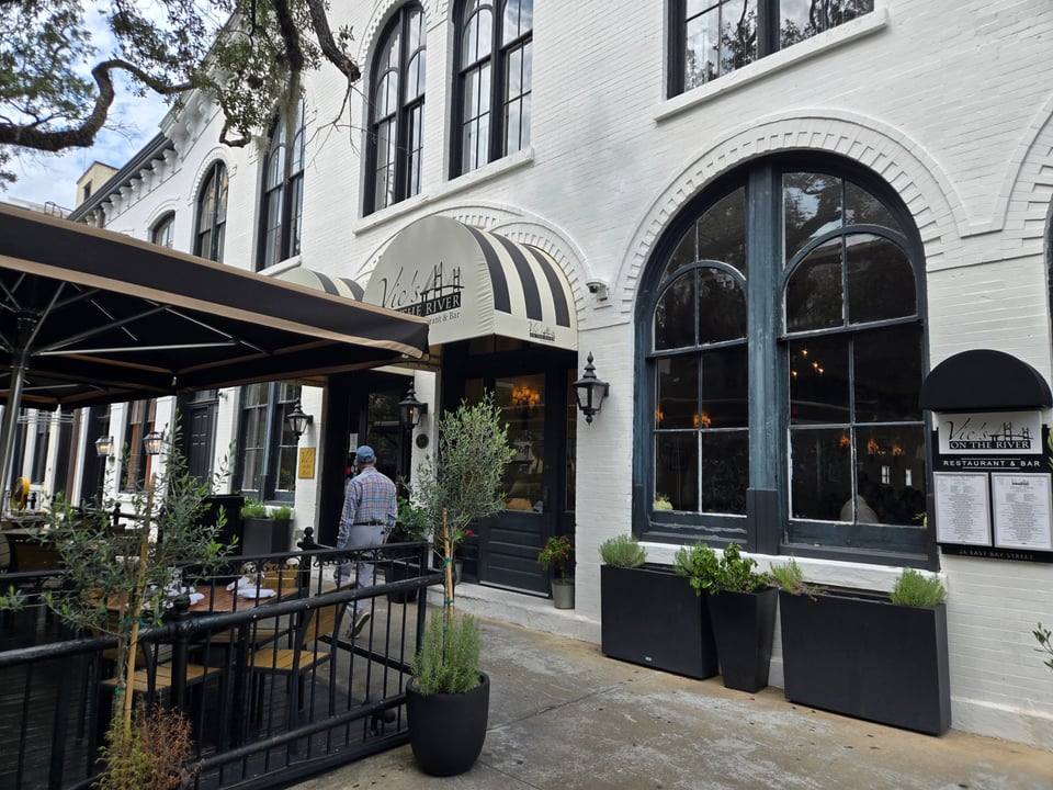 Vic’s on the River entrance beneath cream awnings on a white building.